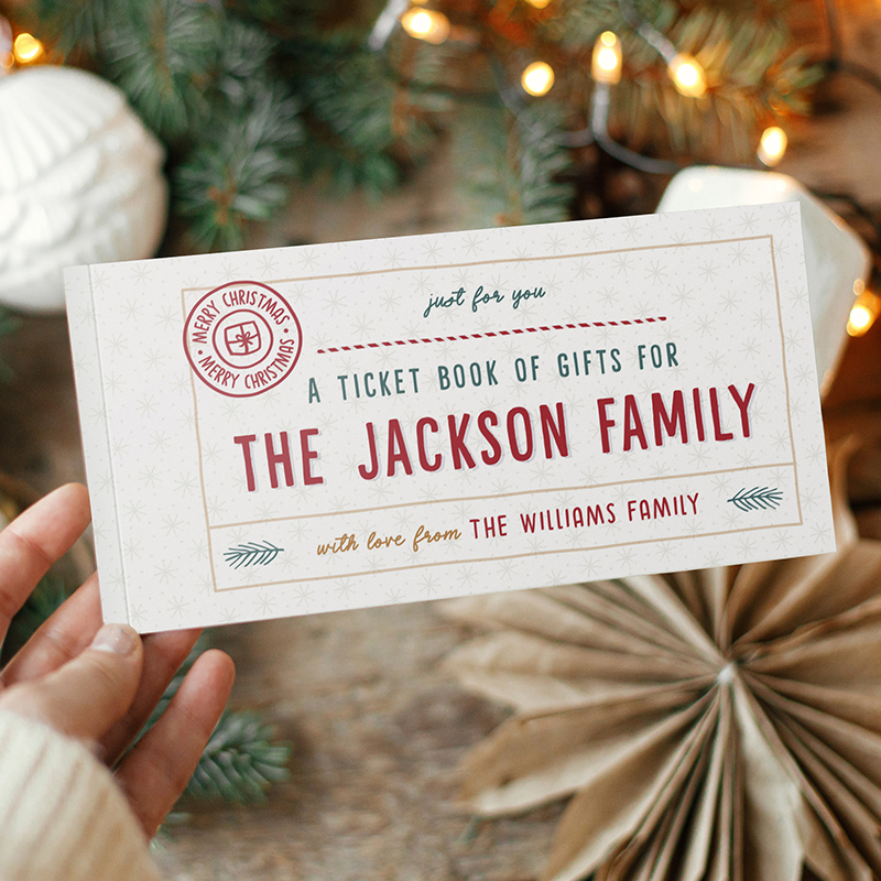 Hands holding a Christmas themed ticket book for "The Jackson Family" with Christmas decorations in the background.